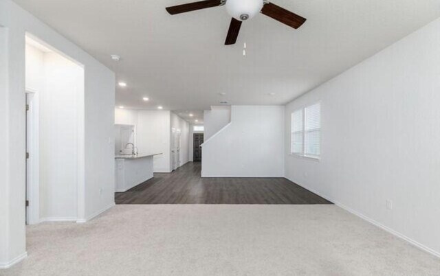 unfurnished living room with baseboards, a ceiling fan, dark colored carpet, a sink, and recessed lighting