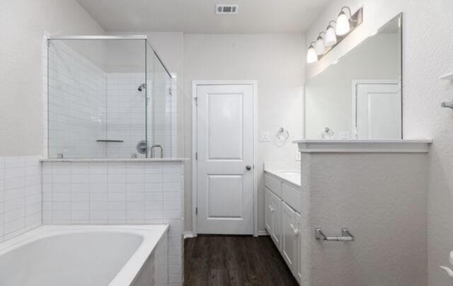 full bath featuring visible vents, wood finished floors, vanity, a shower stall, and a bath