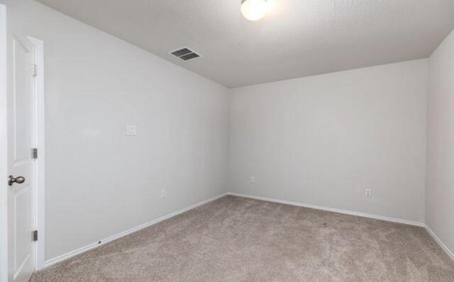 spare room featuring visible vents, light carpet, and baseboards