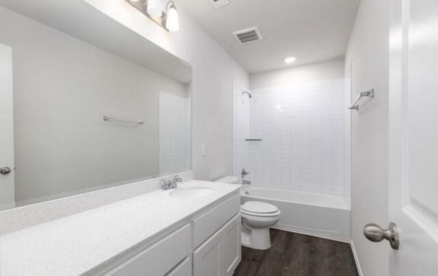 bathroom with shower / bathtub combination, visible vents, toilet, vanity, and wood finished floors