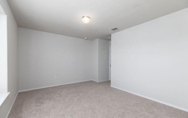 unfurnished room with visible vents, light carpet, and baseboards