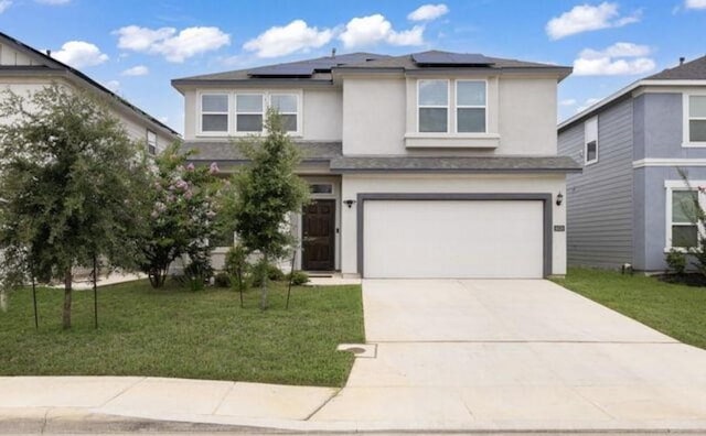 view of front facade with a front yard, concrete driveway, an attached garage, roof mounted solar panels, and stucco siding