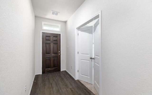 doorway featuring a textured wall, dark wood-type flooring, and visible vents