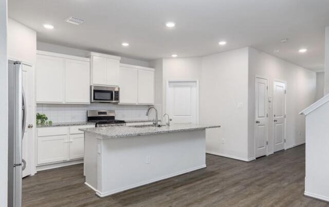 kitchen featuring a kitchen island with sink, stainless steel appliances, a sink, white cabinets, and light stone countertops