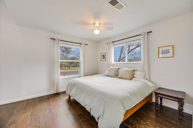 bedroom featuring baseboards, multiple windows, visible vents, and dark wood finished floors