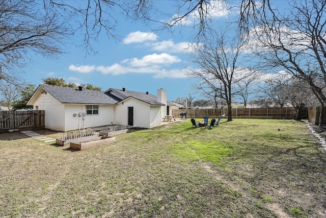 rear view of property featuring a garden, a yard, a fenced backyard, and stucco siding