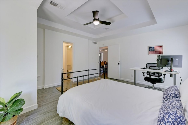 10104 Oak Hollow Cir, Austin, TX 78758 - bedroom featuring a raised ceiling, an office area, wood finished floors, baseboards, and ceiling fan