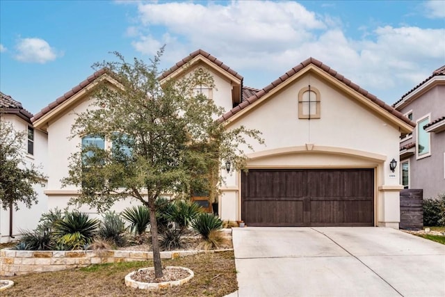 mediterranean / spanish-style home featuring driveway, an attached garage, a tiled roof, and stucco siding