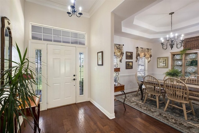 foyer featuring a chandelier, a tray ceiling, dark wood-type flooring, and crown molding