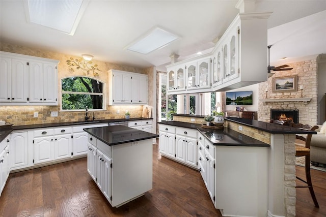 kitchen featuring dark countertops, white cabinetry, glass insert cabinets, and a center island