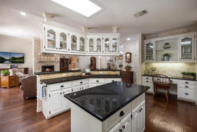 kitchen with visible vents, white cabinets, built in study area, tasteful backsplash, and glass insert cabinets