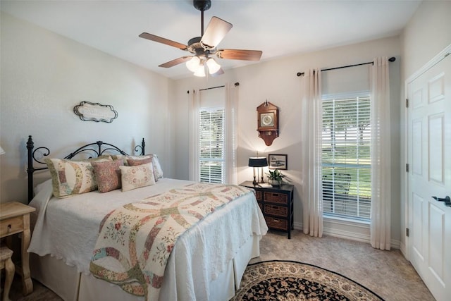 bedroom featuring light carpet, multiple windows, a ceiling fan, and baseboards