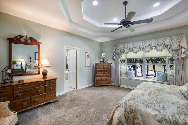 carpeted bedroom featuring ensuite bathroom, recessed lighting, a raised ceiling, and baseboards