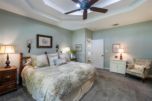 bedroom featuring visible vents, a raised ceiling, baseboards, ceiling fan, and dark carpet