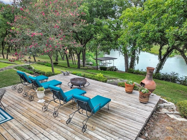 wooden deck featuring an outdoor fire pit and a water view