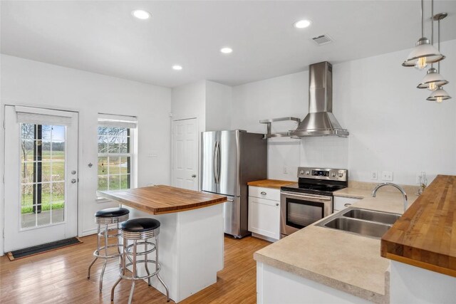 826 Savannah Cv, Elgin, TX 78621 - kitchen featuring butcher block counters, appliances with stainless steel finishes, wall chimney range hood, a sink, and a breakfast bar