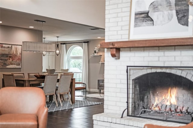 living room with baseboards, visible vents, dark wood-type flooring, a fireplace, and recessed lighting