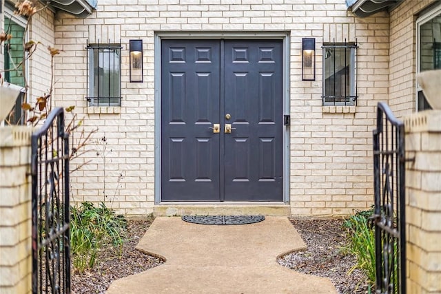 view of exterior entry with brick siding and fence