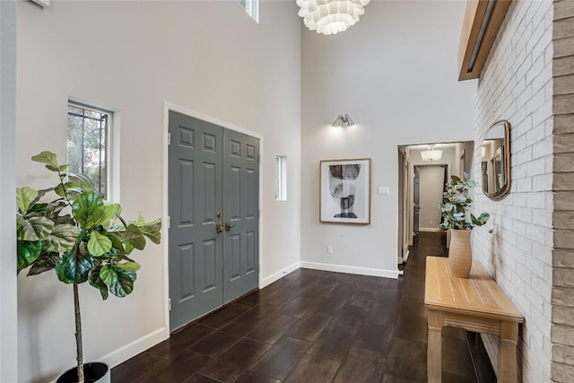 entryway featuring a towering ceiling, baseboards, dark wood finished floors, and a chandelier