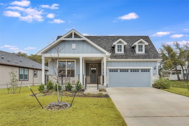 view of front of house featuring roof with shingles, a porch, concrete driveway, board and batten siding, and a front yard