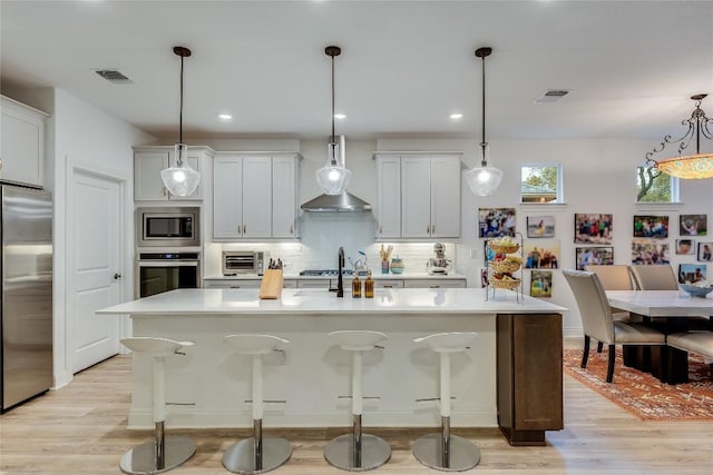 331 Kitty Hawk Rd, Georgetown, TX 78633 - kitchen featuring appliances with stainless steel finishes, light wood-style floors, decorative backsplash, a kitchen island with sink, and recessed lighting