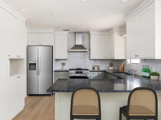 8205 Alabama Dr, Austin, TX 78745 - kitchen with appliances with stainless steel finishes, wall chimney range hood, light wood-type flooring, a peninsula, and backsplash
