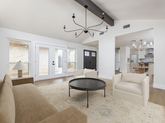 living room featuring visible vents, lofted ceiling with beams, french doors, light wood-style floors, and a chandelier