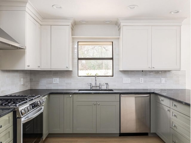 8205 Alabama Dr, Austin, TX 78745 - kitchen featuring stainless steel appliances, wall chimney exhaust hood, tasteful backsplash, dark stone countertops, and white cabinetry
