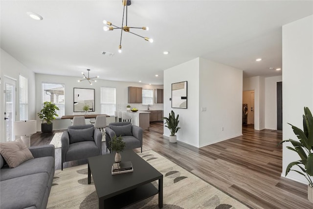 living area with a notable chandelier, light wood finished floors, recessed lighting, visible vents, and washer and dryer