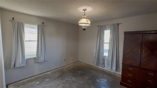 empty room featuring plenty of natural light, concrete floors, and a textured ceiling