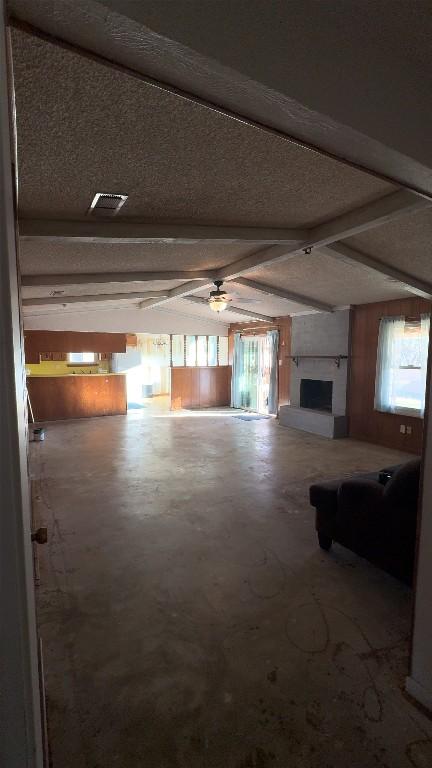 unfurnished living room featuring vaulted ceiling with beams, ceiling fan, plenty of natural light, and a fireplace