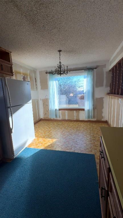 kitchen with a chandelier, a textured ceiling, and freestanding refrigerator