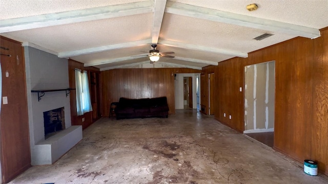 unfurnished living room featuring vaulted ceiling with beams, a fireplace, visible vents, wood walls, and a textured ceiling