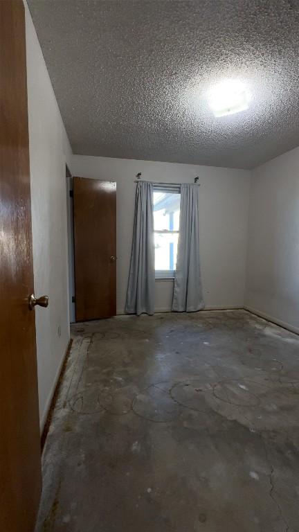 unfurnished room featuring a textured ceiling and unfinished concrete flooring