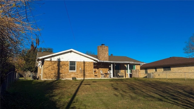 rear view of property featuring a yard, cooling unit, fence, and a chimney