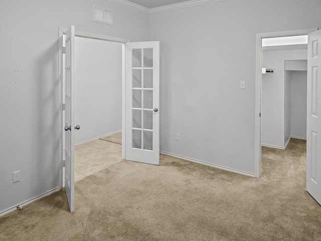 unfurnished room featuring visible vents, ornamental molding, french doors, and light colored carpet