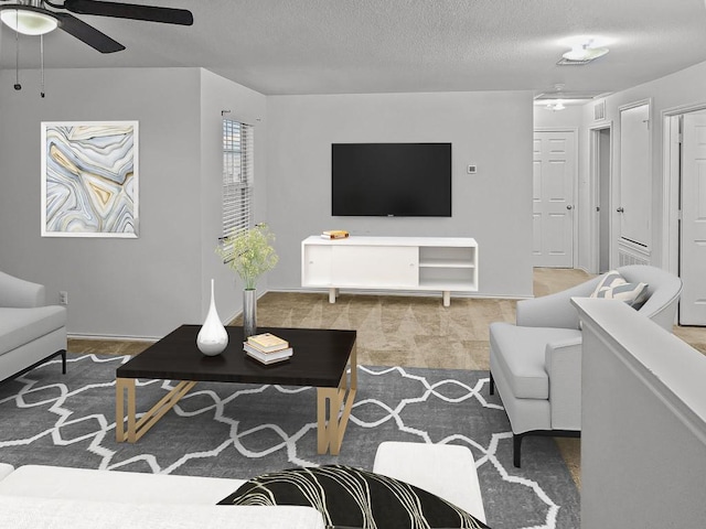 carpeted living area featuring ceiling fan and a textured ceiling