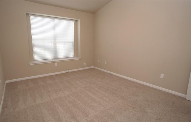 empty room featuring baseboards and light colored carpet