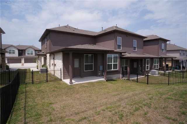 rear view of house with a yard, a fenced backyard, stone siding, and a patio