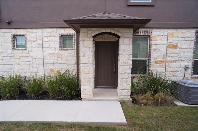 409 Epiphany Ln, Pflugerville, TX 78660 - view of exterior entry with stone siding, central AC unit, and stucco siding