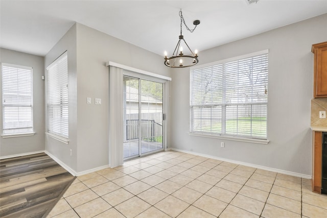 unfurnished dining area with a notable chandelier and baseboards