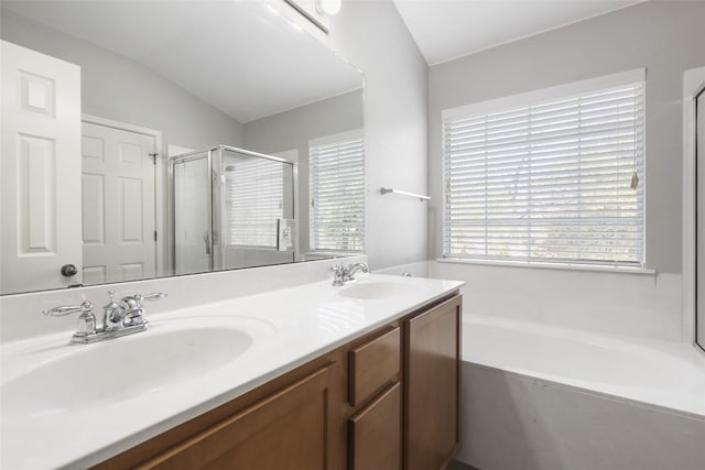 bathroom with double vanity, a garden tub, a shower stall, and a sink