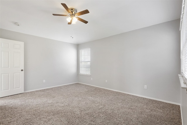 carpeted empty room featuring a ceiling fan and baseboards