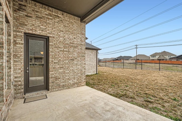 entrance to property featuring brick siding, a patio, and fence