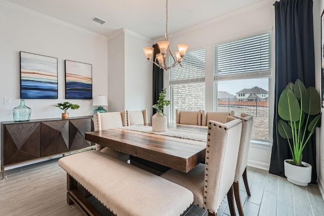 dining space with light wood-style flooring, visible vents, baseboards, ornamental molding, and an inviting chandelier