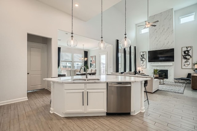 kitchen with an island with sink, open floor plan, light countertops, white cabinetry, and a sink