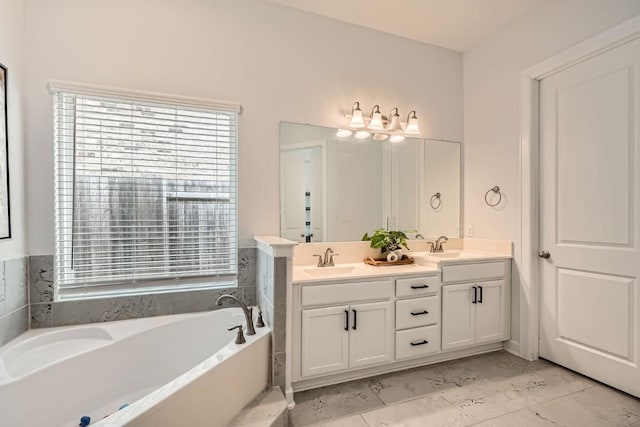 bathroom with marble finish floor, double vanity, a sink, and a bath