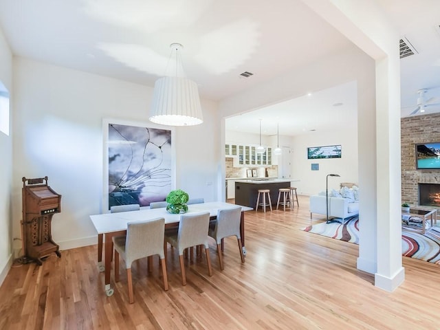 2312 W 8th St, Austin, TX 78703 - dining area featuring light wood-style flooring, a fireplace, and baseboards