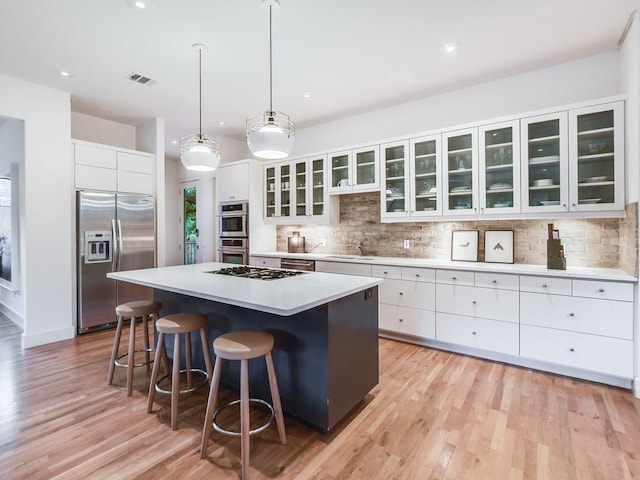 2312 W 8th St, Austin, TX 78703 - kitchen featuring stainless steel appliances, a kitchen island, a breakfast bar area, white cabinetry, and recessed lighting
