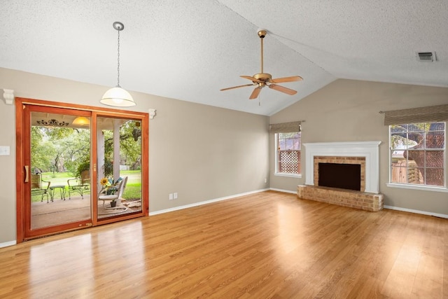 unfurnished living room with light wood-style flooring, a fireplace, visible vents, and a wealth of natural light